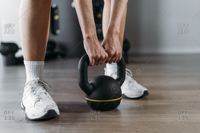 Close-up of woman lifting kettle bell while standing in gym