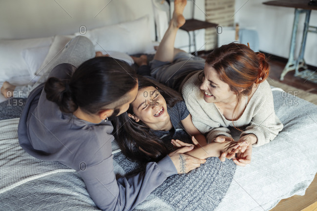 Parents and daughter having fun while lying on bed at home
