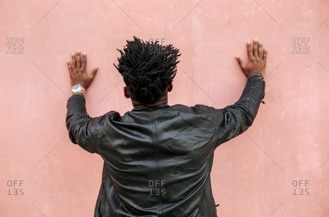 Mid adult man with locs standing in front of pink wall