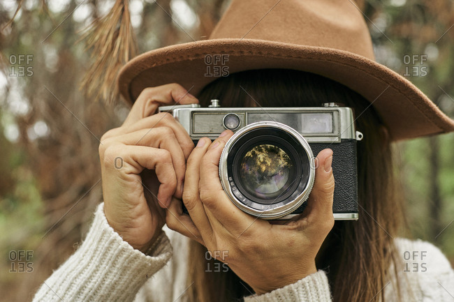 Woman photographing through vintage camera in forest