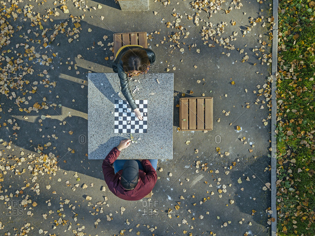 Couple playing chess at table in park during autumn
