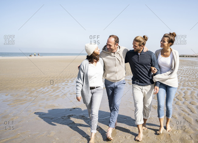 Happy couples with arm around walking at beach
