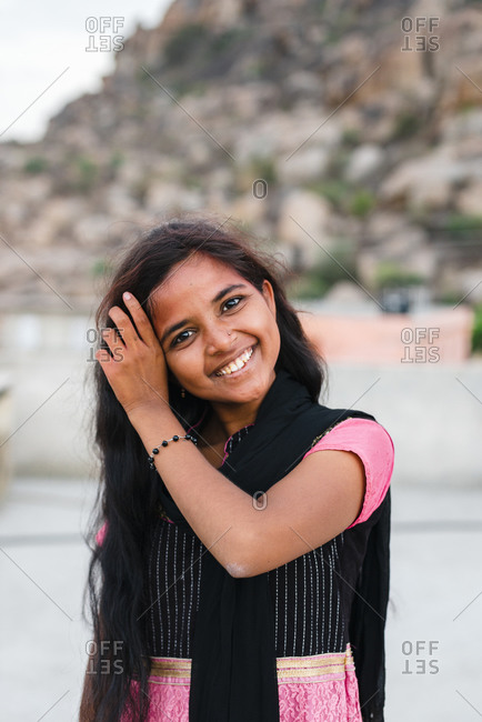 Hampi, Karnataka, India - April 07, 2019: Smiling Indian woman touching long black hair wearing traditional clothes