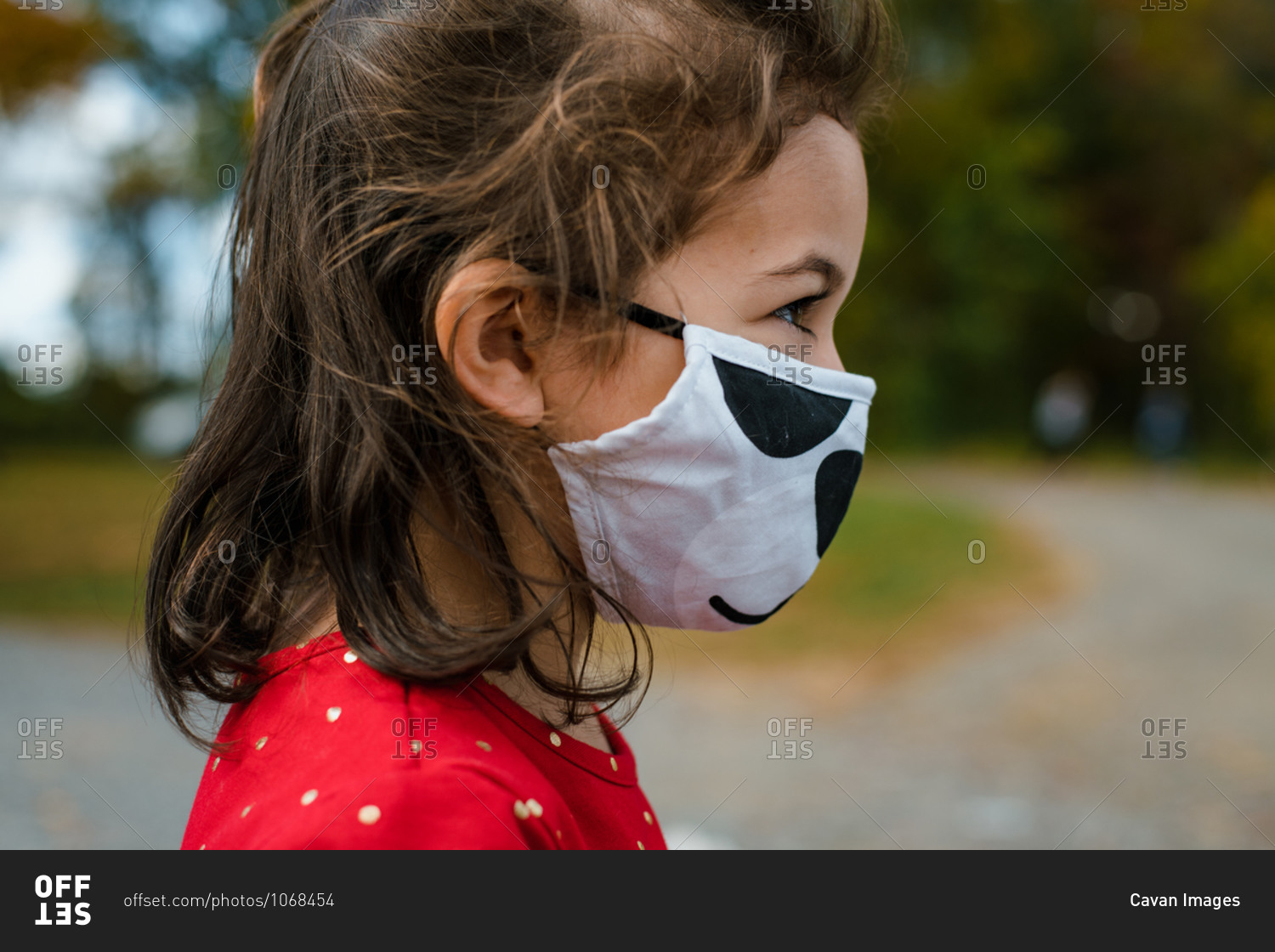 Preschool age girl wearing protective face mask outside in fall