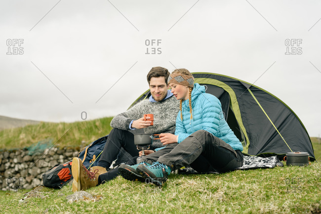 Hikers brewing beverage near tent