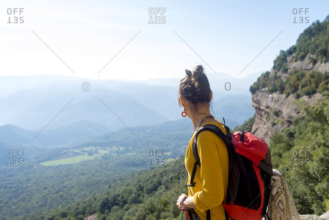 Rear view of a young woman standing on high mountain looking at view