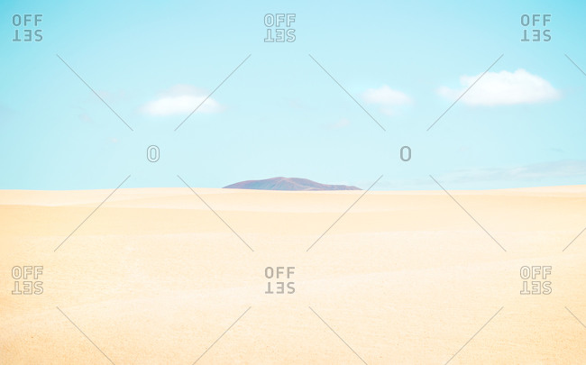 Desert landscape with a mountain between the dunes on sunny day.
