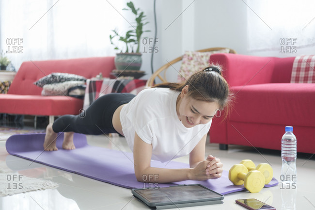 Fit woman doing yoga plank and watching online tutorials.