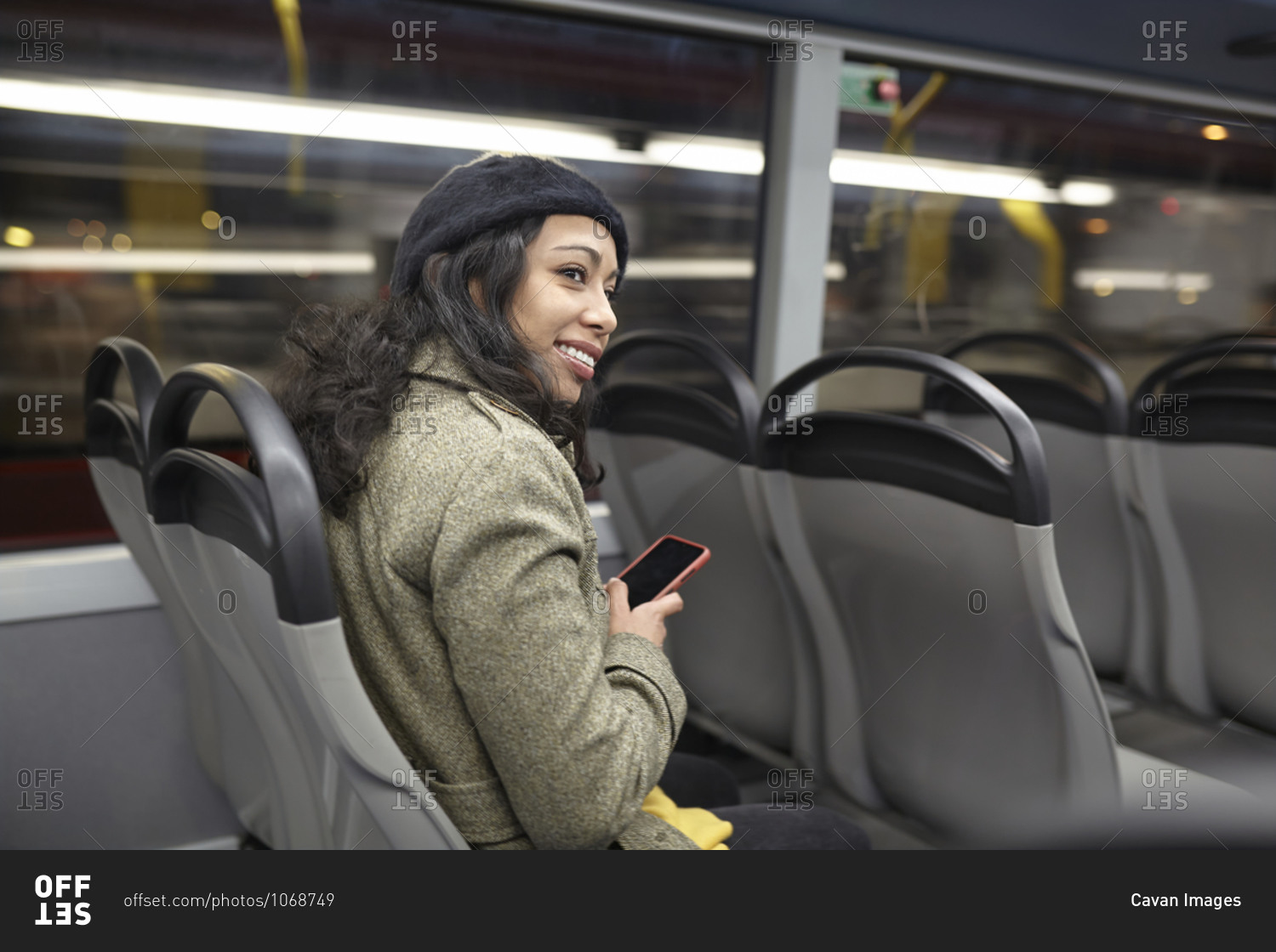 Smiling woman sitting in a public bus at night stock photo - OFFSET