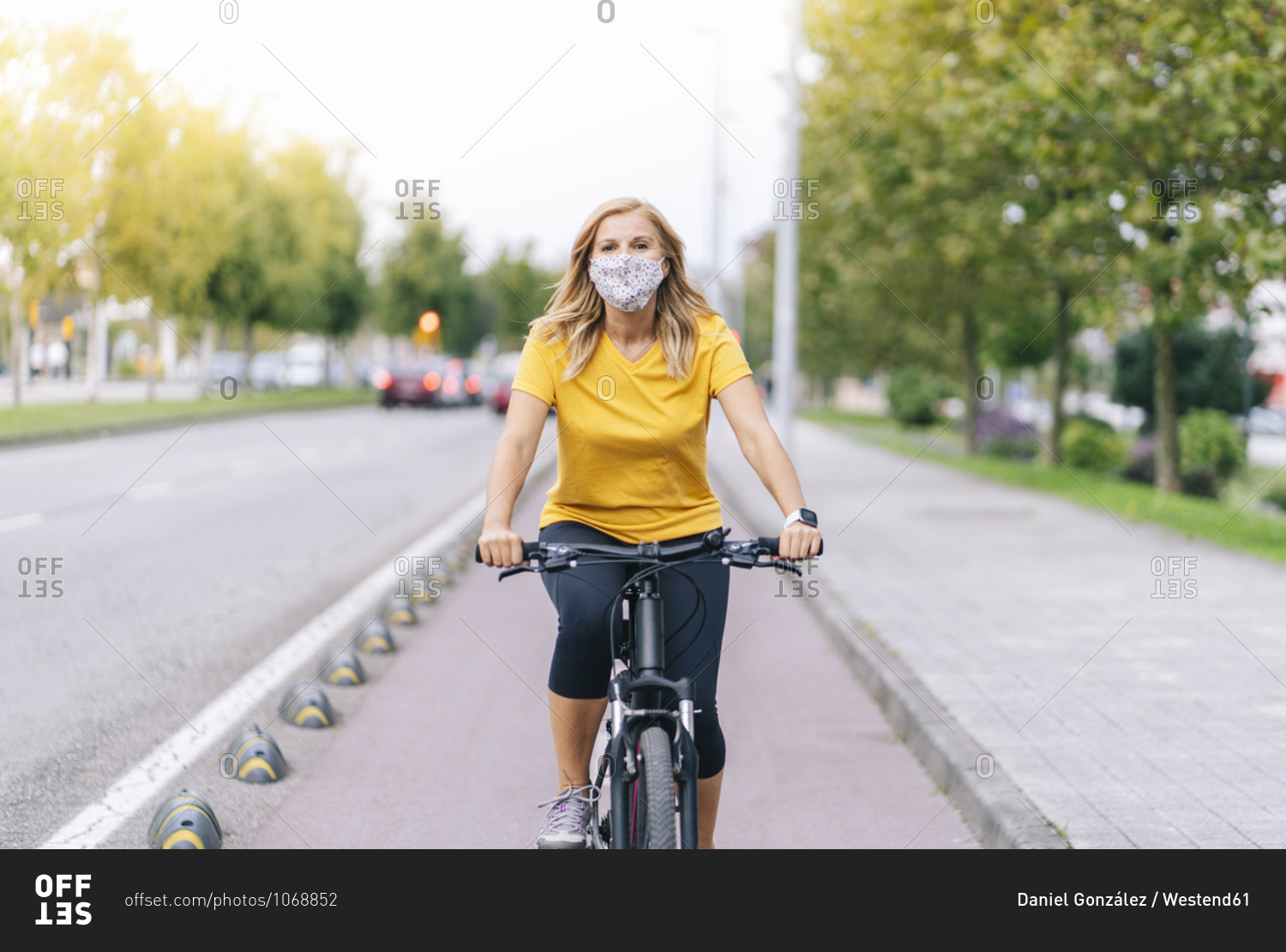 Woman wearing protective face mask cycling on bicycle lane in city
