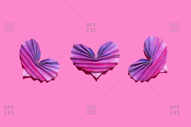 Studio shot of three pink and purple origami hearts