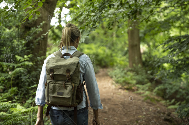 Senior woman walking with backpack in forest