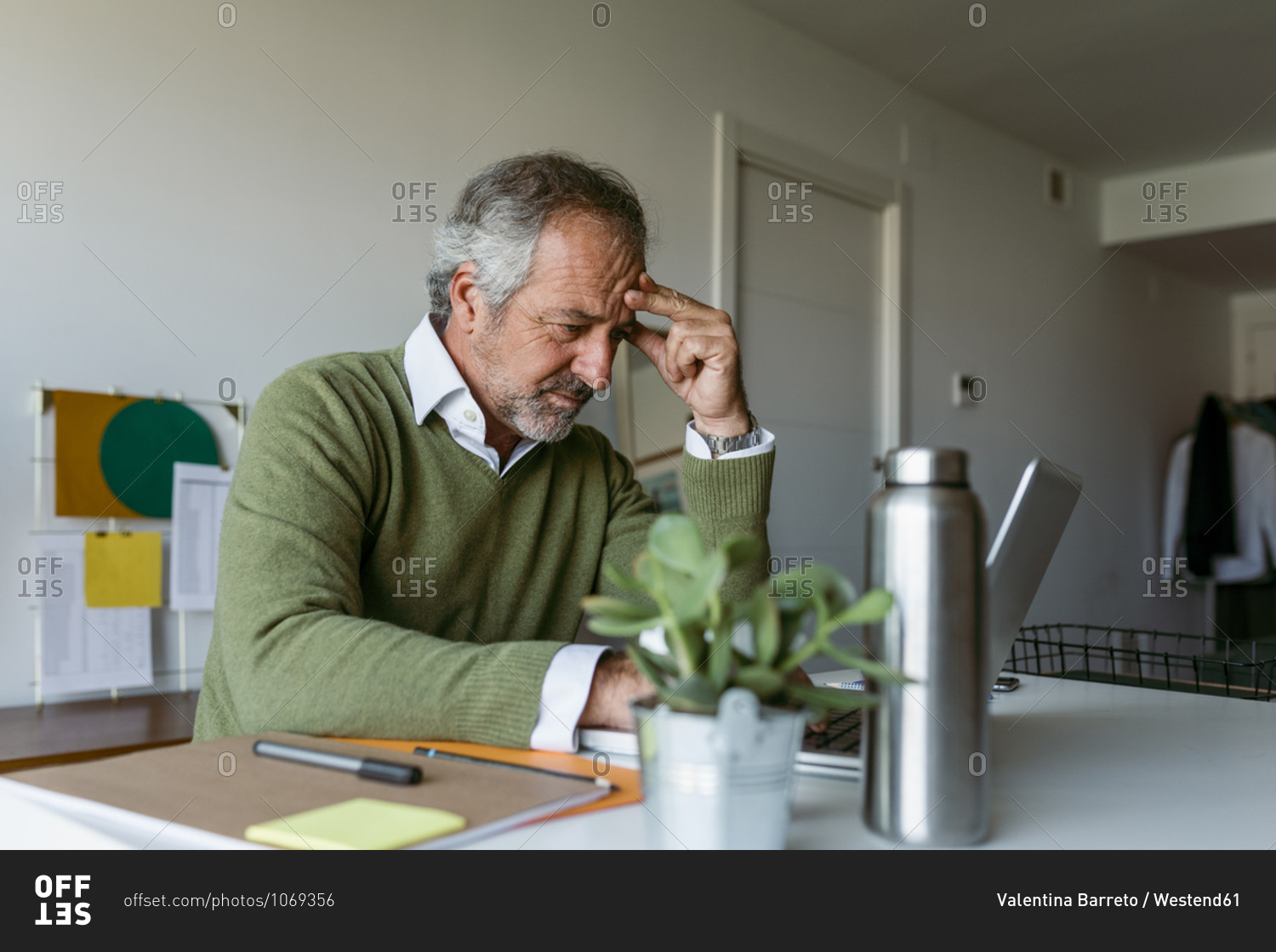 Mature man worried while working on laptop at home