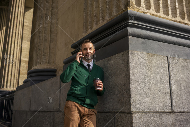 Businessman talking on mobile phone while leaning on pillar of Kazan Cathedral at Saint Petersburg- Russia