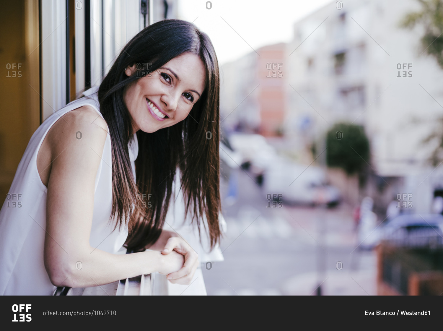 Smiling woman leaning out of window while standing in house