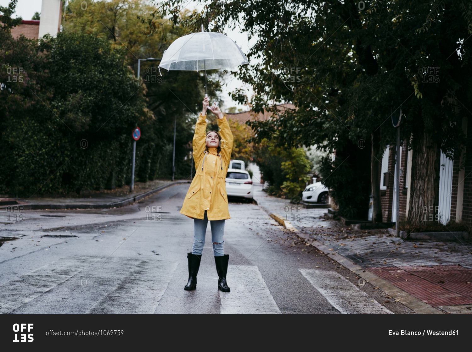 Girl wearing raincoat and jump boot standing on road in city