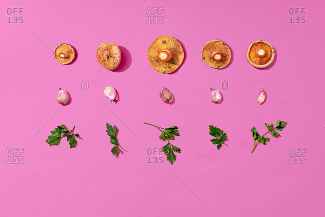 Mushrooms- garlic and parsley arranged on pink background