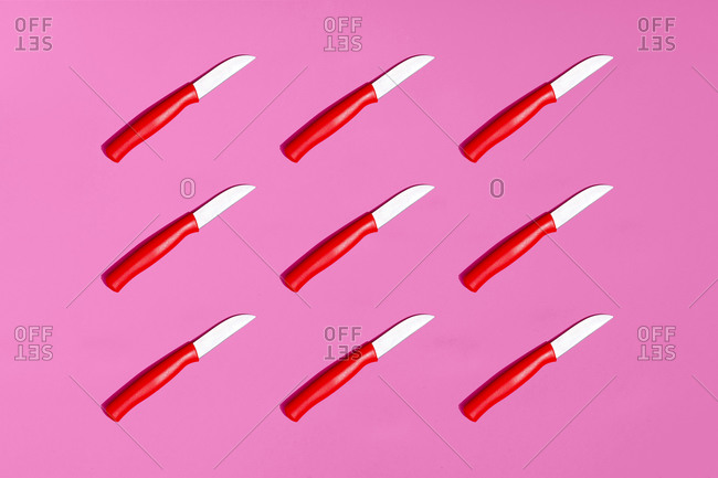 Full frame of table knives on pink background