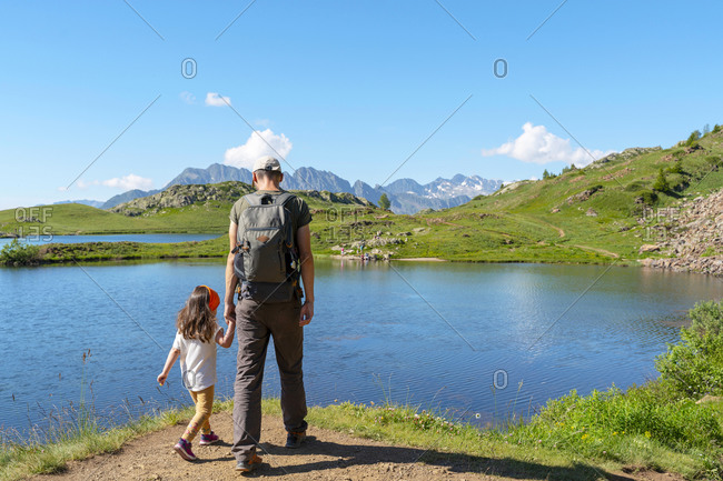 Father and daughter looking at view while walking on walkway during sunny day