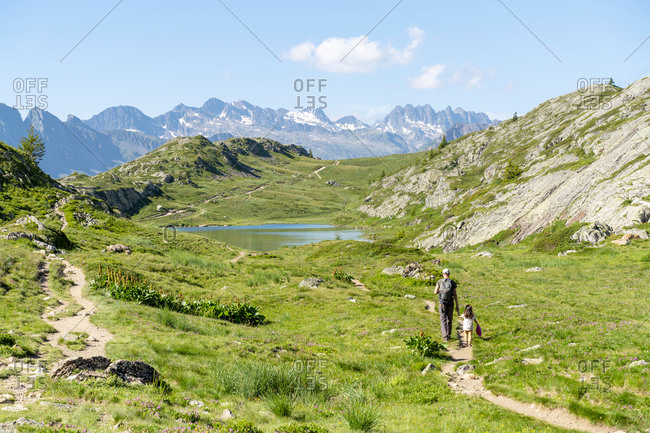 Father and daughter hiking in mountain during summer on sunny day