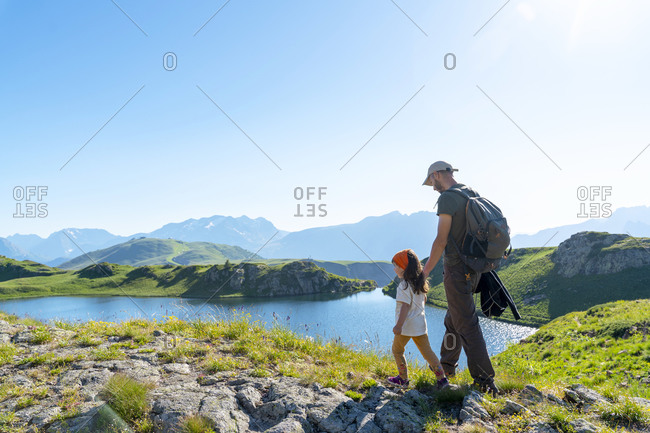 Father and daughter walking on meadow during sunny day