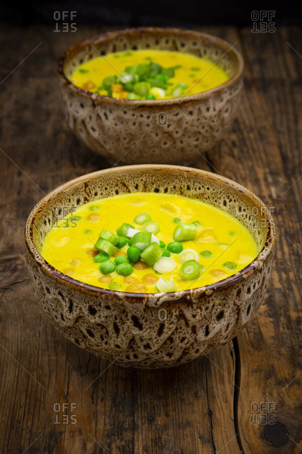 Two bowls of vegan coconut soup with green peas- chick-peas- scallion and turmeric