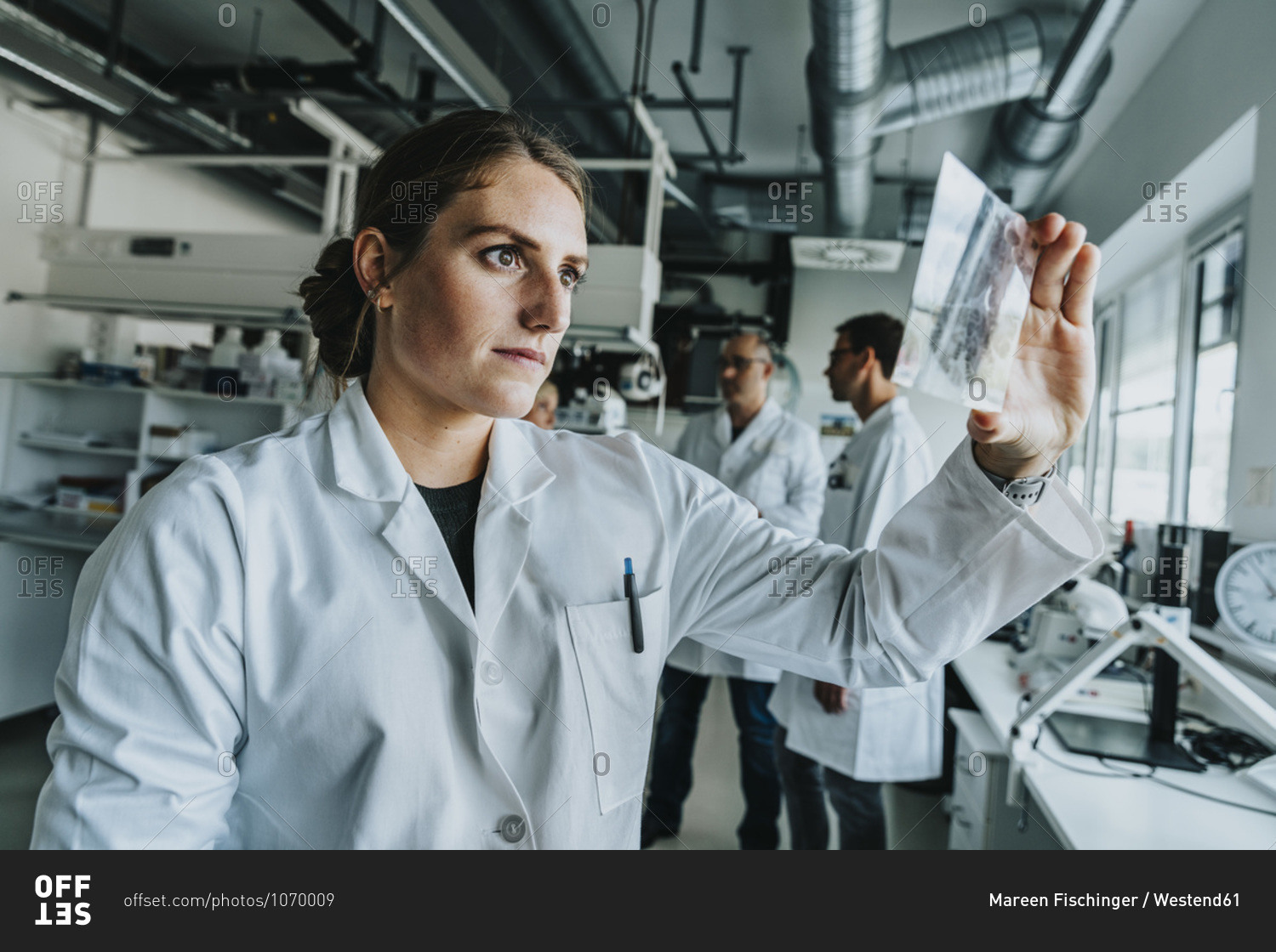 Young woman examining human brain slide while standing with coworker in background at laboratory