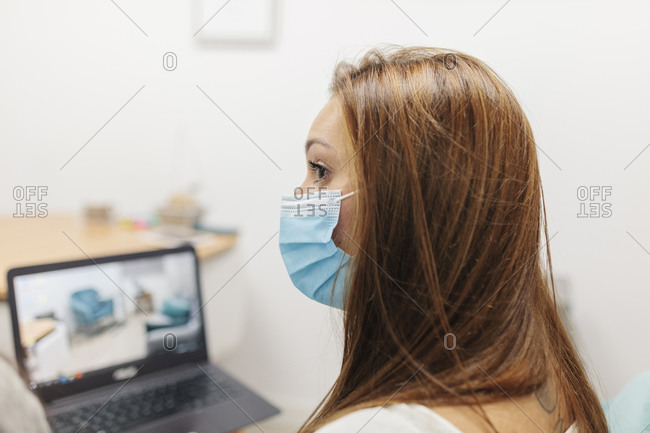 Psychologist wearing face mask using laptop while working at laptop
