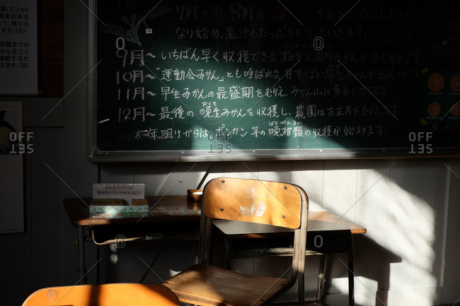 Wakayama, Japan - November 16, 2017: Desk and chairs in front of a blackboard in a classroom with Japanese writing