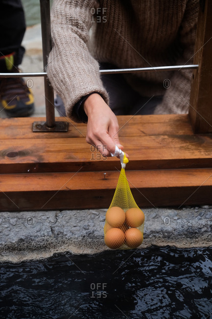 Person making onsen tamago traditional Japanese low temperature eggs by slow cooking them in the hot waters of onsen in Japan