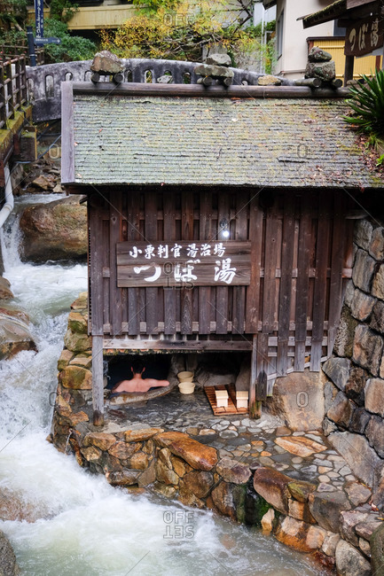 Wakayama, Japan - November 18, 2017: Flowing river beside building enclosing a natural Japanese onsen hot spring with man bathing inside
