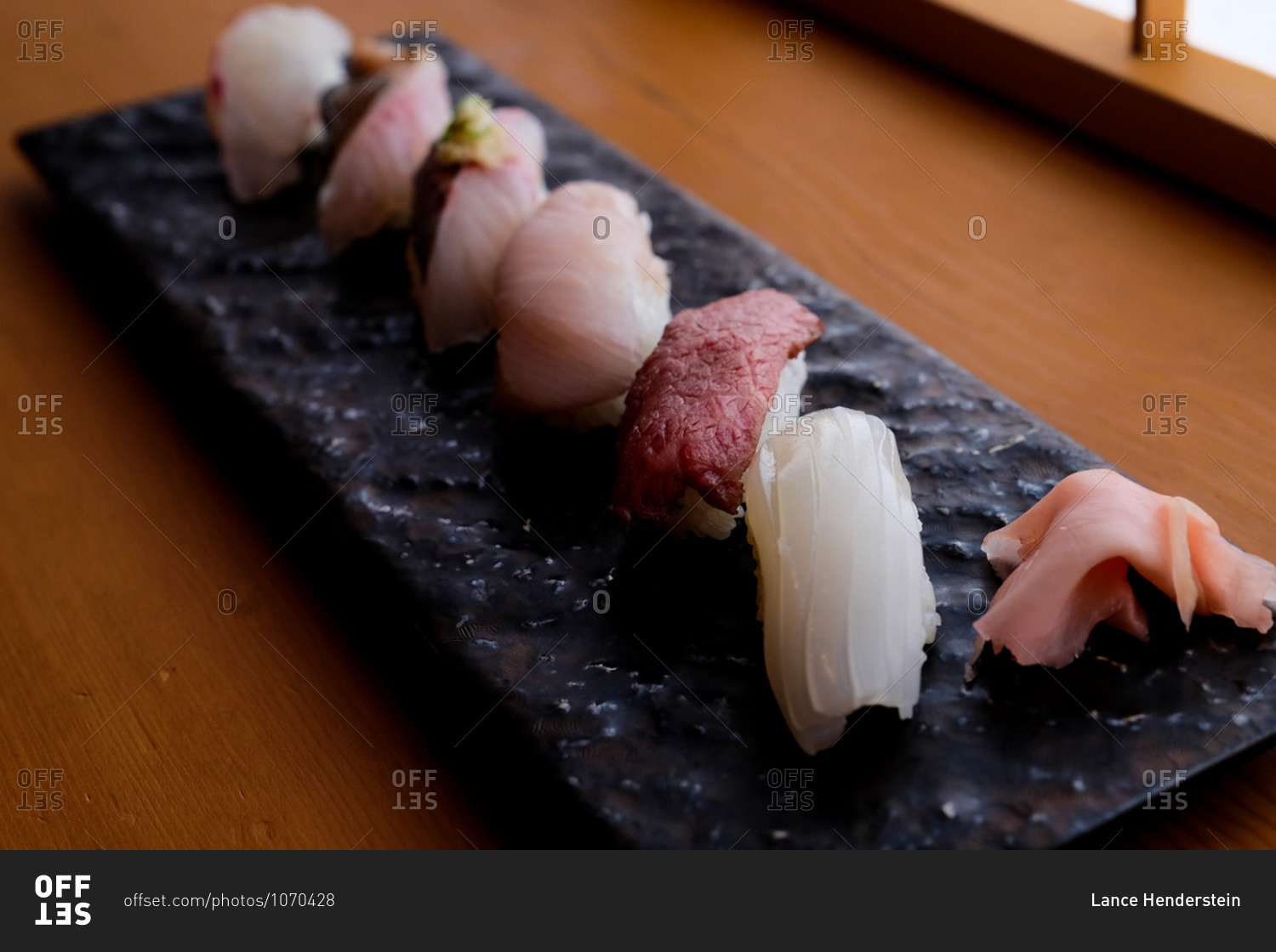 Close up of a sashimi seafood dish on a slate tray on wooden table viewed from above