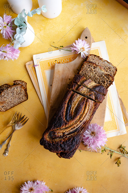 Banana bread with no added sugar sliced and being served on yellow surface with candles and flowers