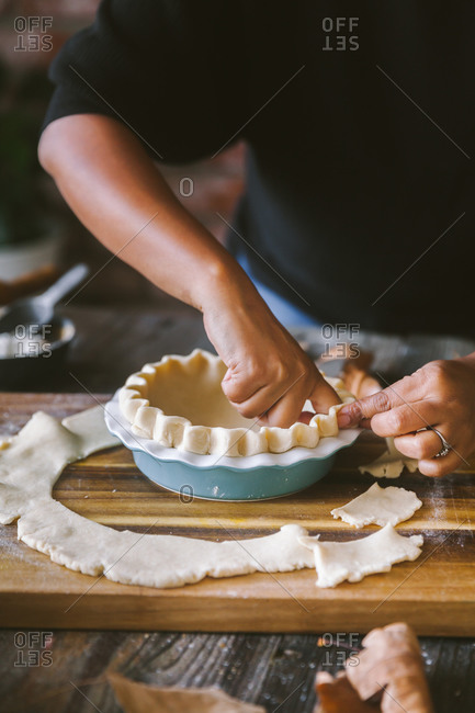 Baker preparing pie crust on rustic table by hand