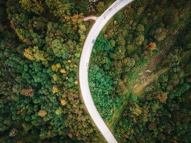 Spectacular drone view of roadway with driving cars leading through amazing green woods