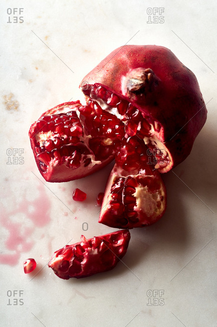 Fresh ripe halved pomegranate and seeds on white marble background