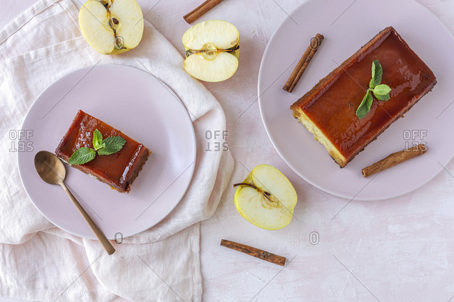 Top view composition of yummy aromatic homemade apple pudding with cinnamon and green mint leaves served on table with fresh sliced fruits