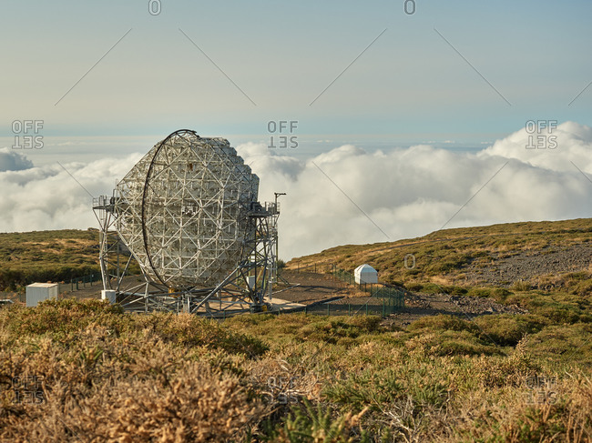 Amazing view of modern telescopes on dark mountaintop against cloudy sky at astronomical observatory on island of La Palma in Spain