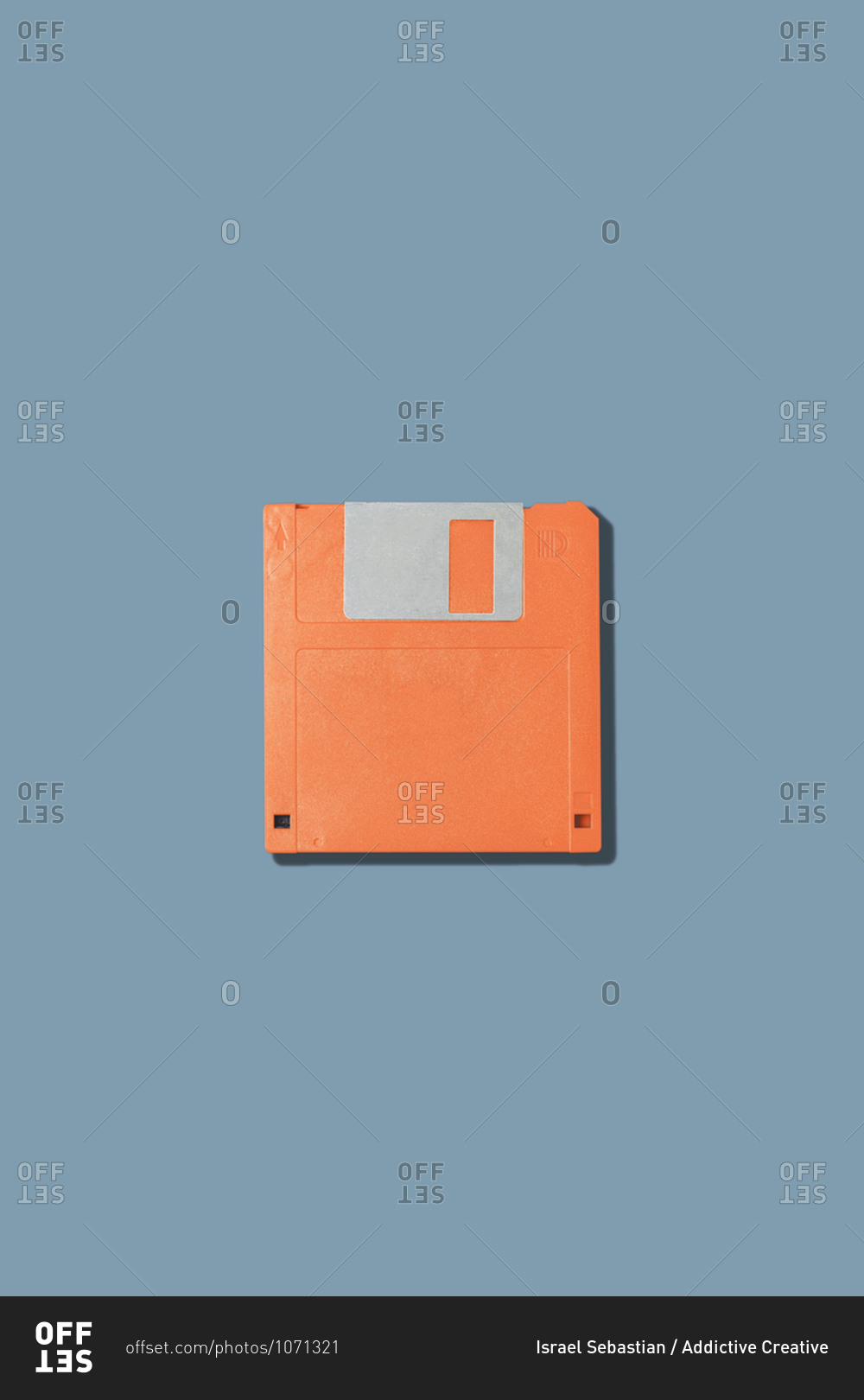 Top view of old fashioned orange magnetic floppy disk for computer placed on gray background