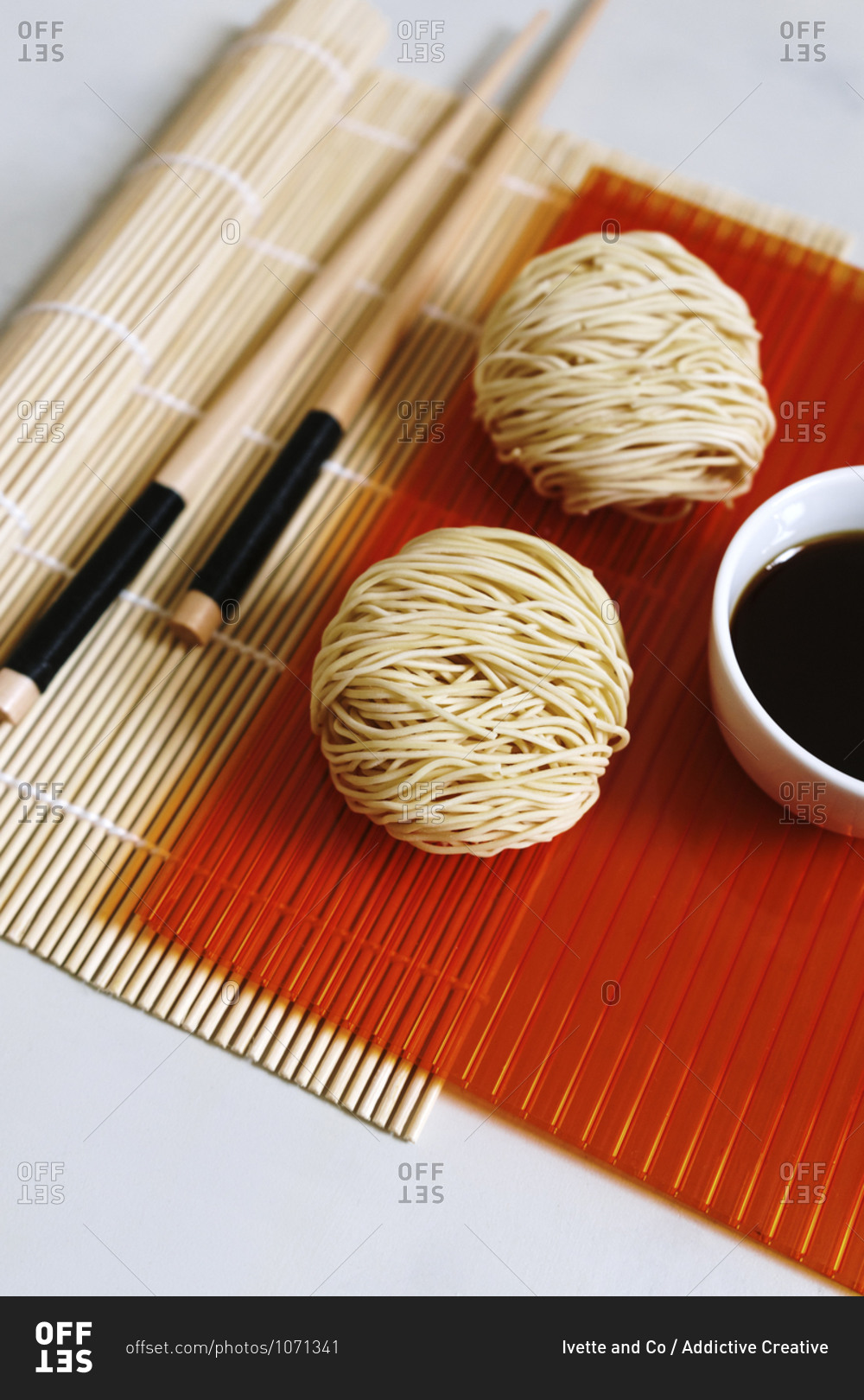 High angle of arrangement of round shaped dry noodles and soy sauce on table with wooden chopsticks