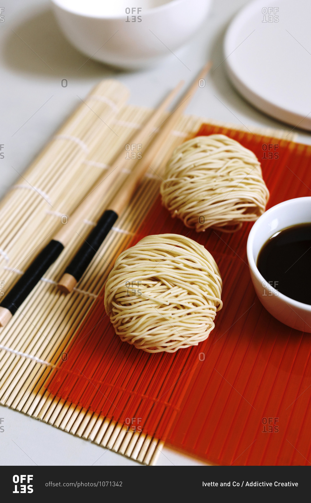 High angle of arrangement of round shaped dry noodles and soy sauce on table with wooden chopsticks