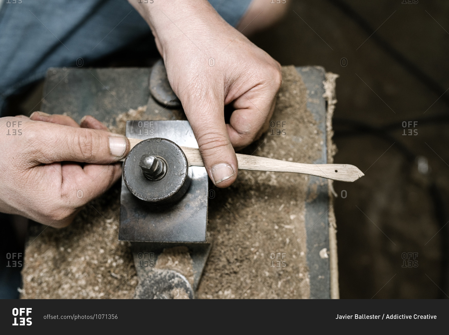 From above of anonymous male carpenter grinding wooden details while making handmade folding fans in messy workshop
