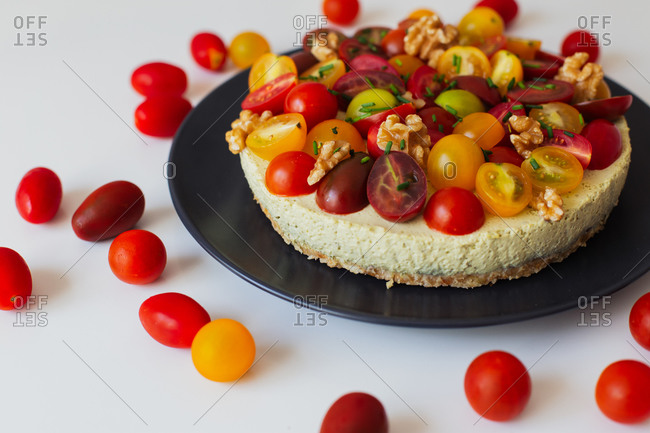 Palatable aromatic homemade quiche with colorful fresh tomatoes and walnuts served on black ceramic plate