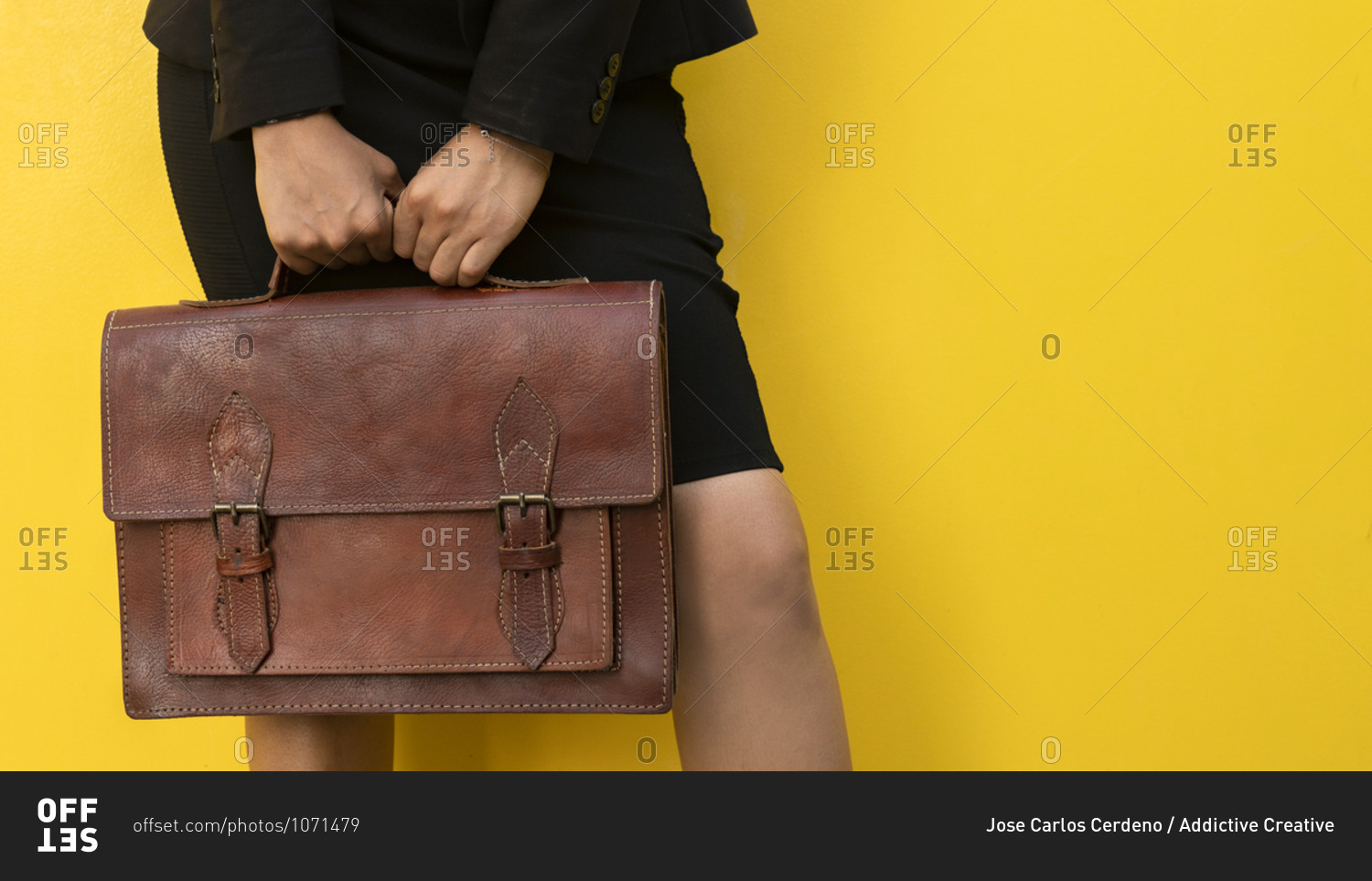 Crop anonymous female in skirt with stylish brown leather handbag standing against yellow background