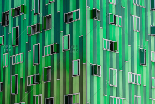 Corner of part of contemporary building with vivid green facade and opened windows
