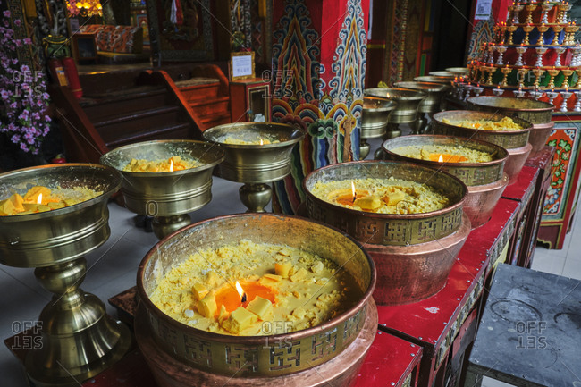 Candles of butter milk of yak in Buddhist shrine with burning flames in praying holy place in China