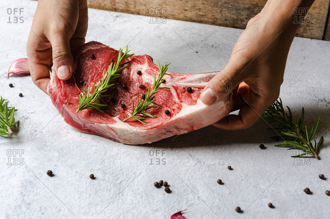 Unrecognizable chef preparing raw t bone beef steak for dinner in kitchen