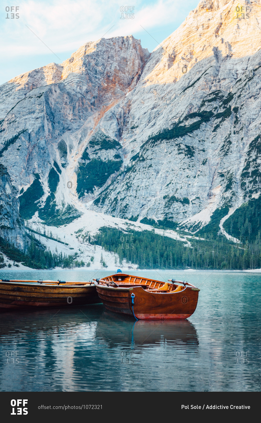 Wooden boat floating on turquoise water of calm lake on background of majestic landscape of highlands