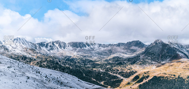 Majestic panoramic scenery of rough rocky slopes of Pyrenees mountain range covered with snow under cloudy sky in El Pas de la Casa