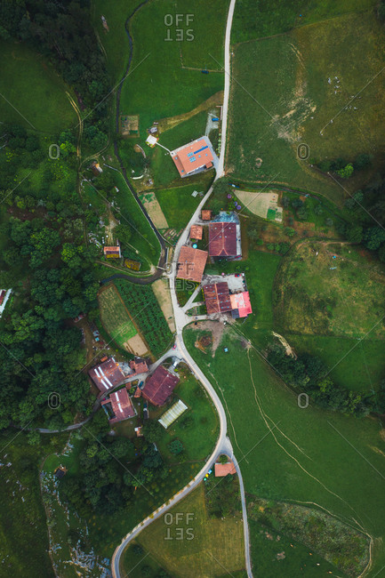 Overhead view of building roofs and narrow roadways between green meadows and trees in Basque Country